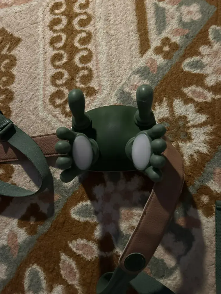 Top view of the Nodly massager on a patterned rug, its two white massage plates facing up